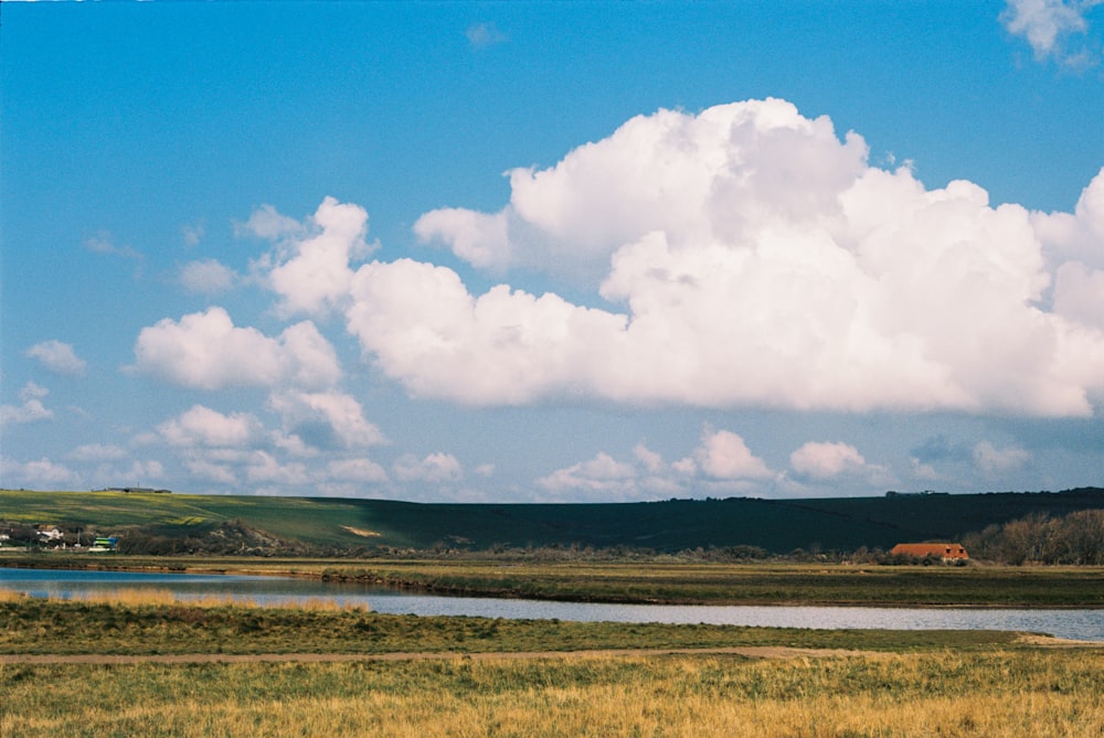 green grass field under white clouds and blue sky during daytime