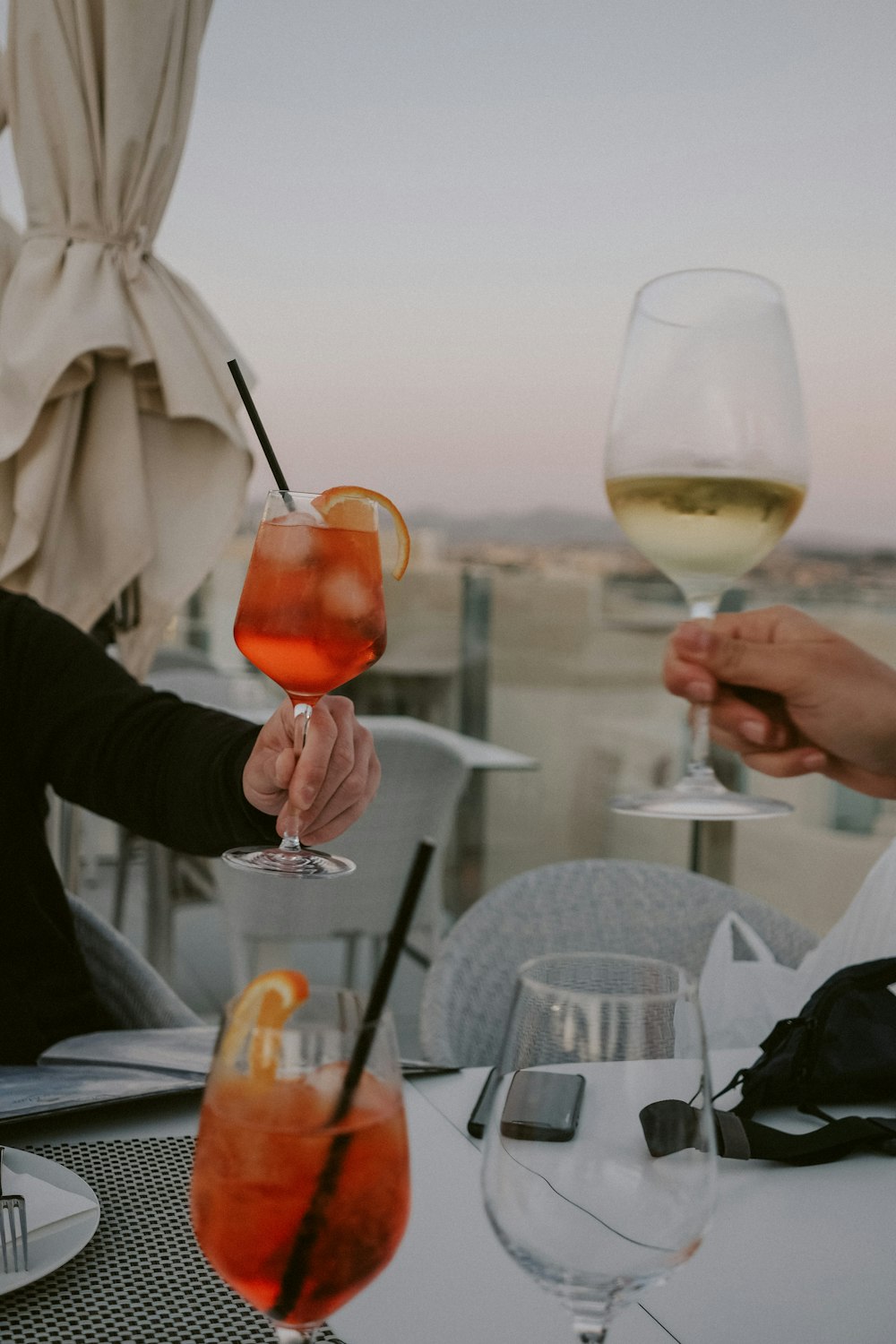 person holding clear wine glass with orange liquid