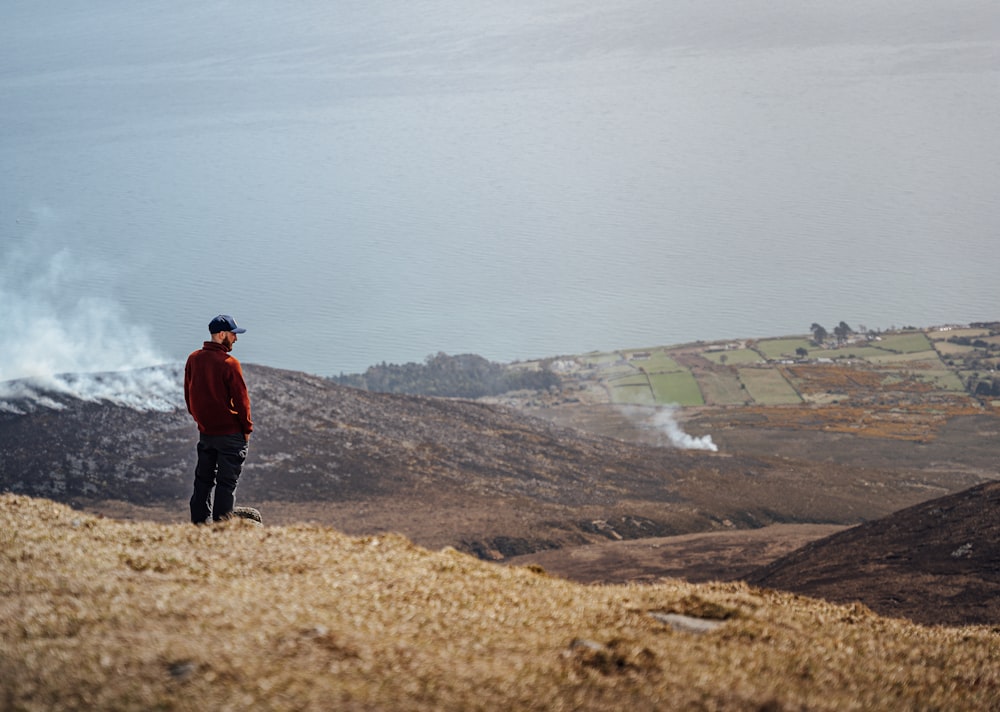 man in red jacket standing on brown field during daytime