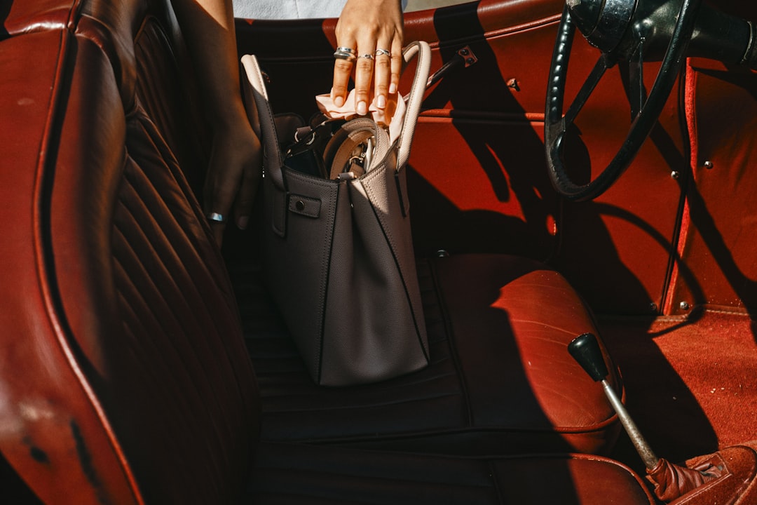 person in black pants sitting on brown leather car seat