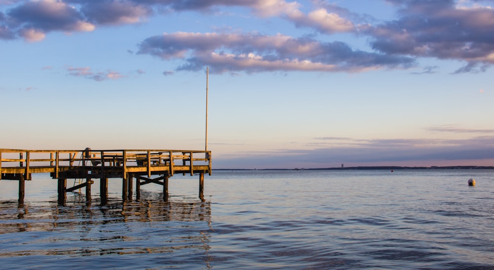 brown wooden dock on sea during sunset