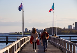 man in red jacket walking on wooden bridge during daytime