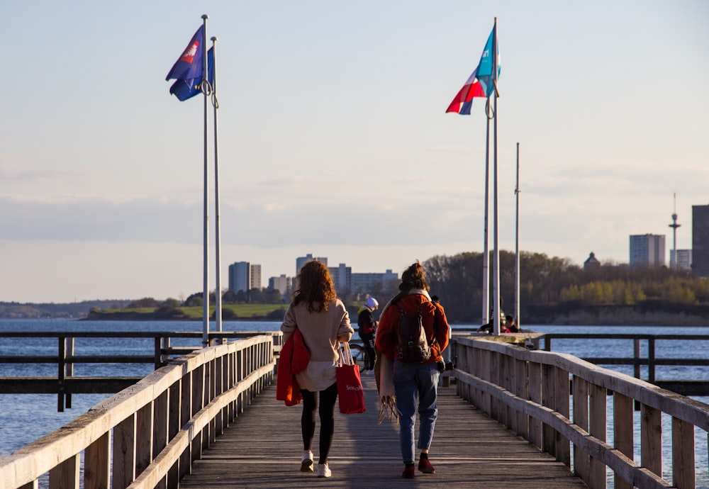 man in red jacket walking on wooden bridge during daytime