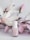 A bottle of Essie nail polish is positioned in front of soft pink and white artificial flowers. The background features delicate pastel tones, giving a sense of elegance and subtle beauty.
