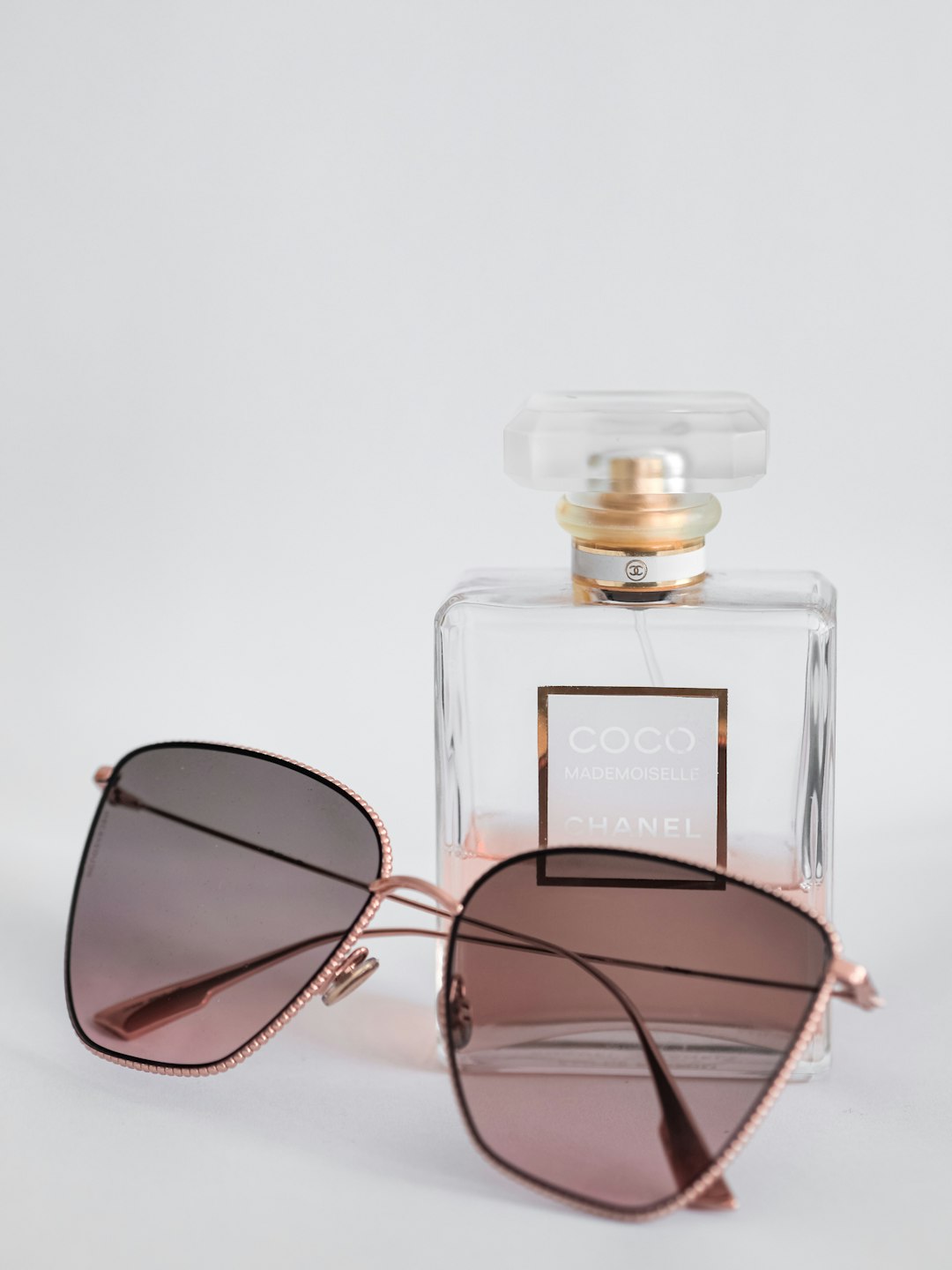 black framed sunglasses beside perfume bottle