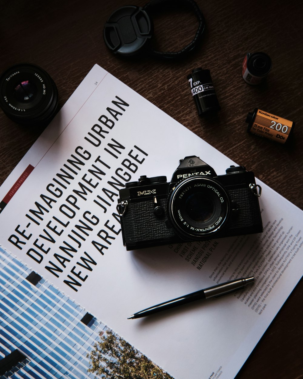 Fotocamera reflex digitale Nikon nera accanto a penna a scatto marrone e nera su carta bianca per stampante