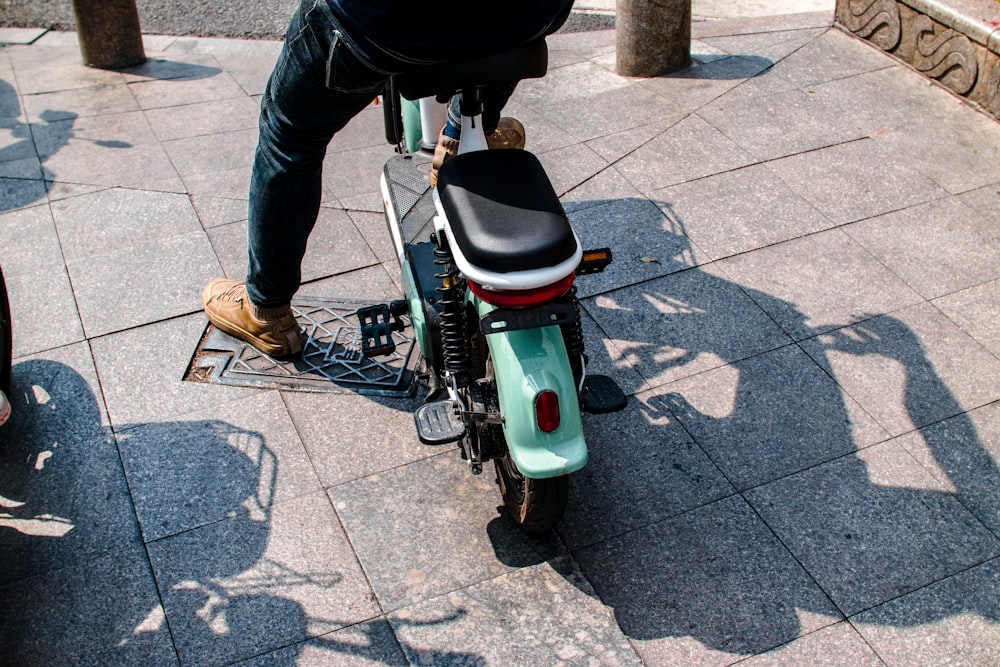 person in black jacket riding white and green motor scooter