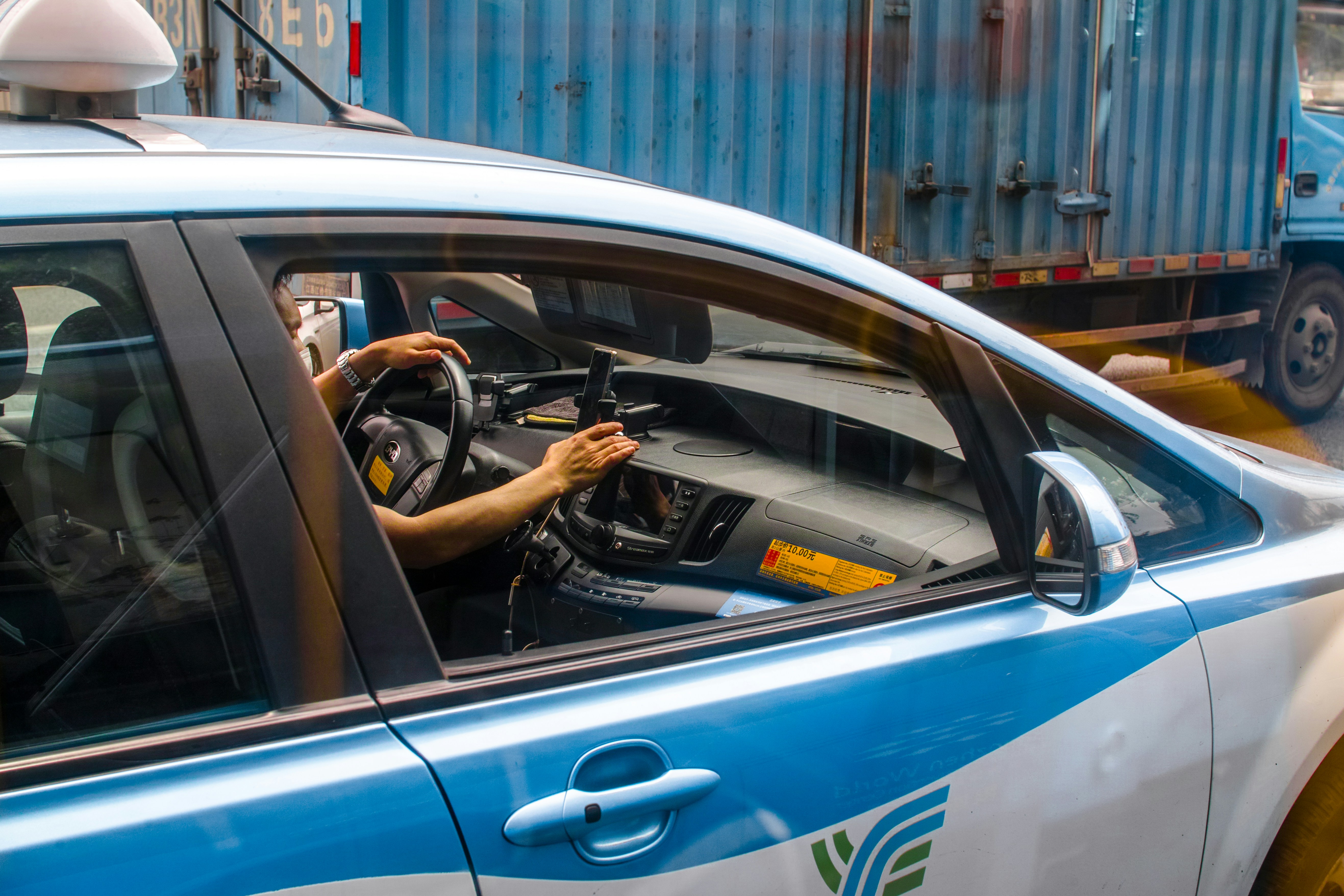 person driving blue car during daytime