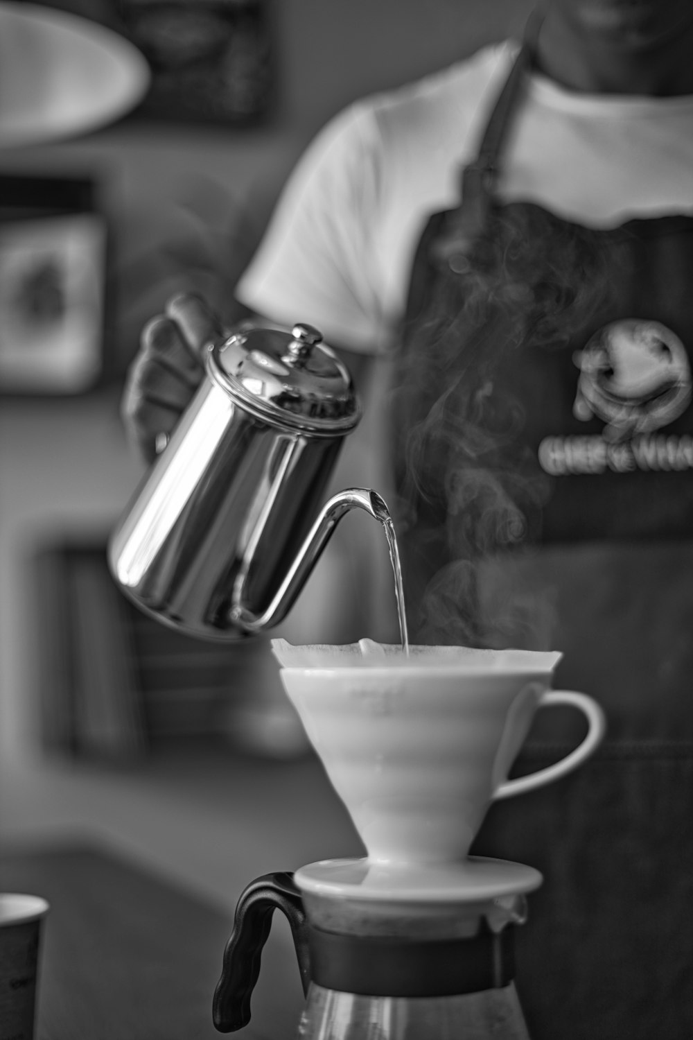 grayscale photo of woman pouring water on white ceramic teacup