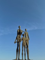 Family 3D sculpture featuring three figures in a warm, connected stance.