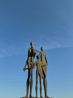 Family 3D sculpture featuring three figures in a warm, connected stance.