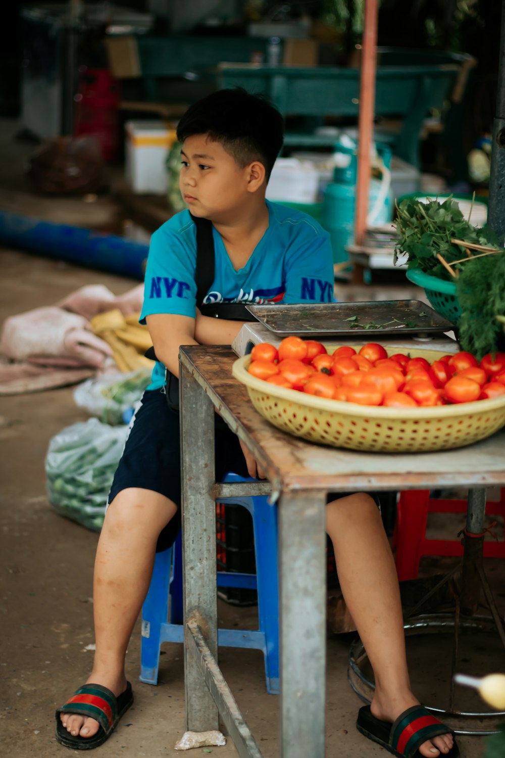 woman in blue and white shirt standing in front of fruit stand