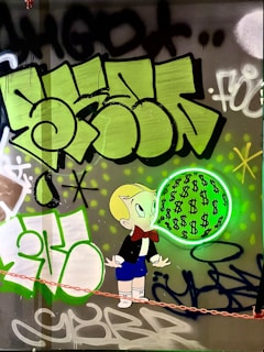A cartoon character with blonde hair and a red bow tie is depicted blowing a bubble filled with dollar signs. The background features vibrant graffiti art in shades of green, black, and white with abstract shapes and lettering.