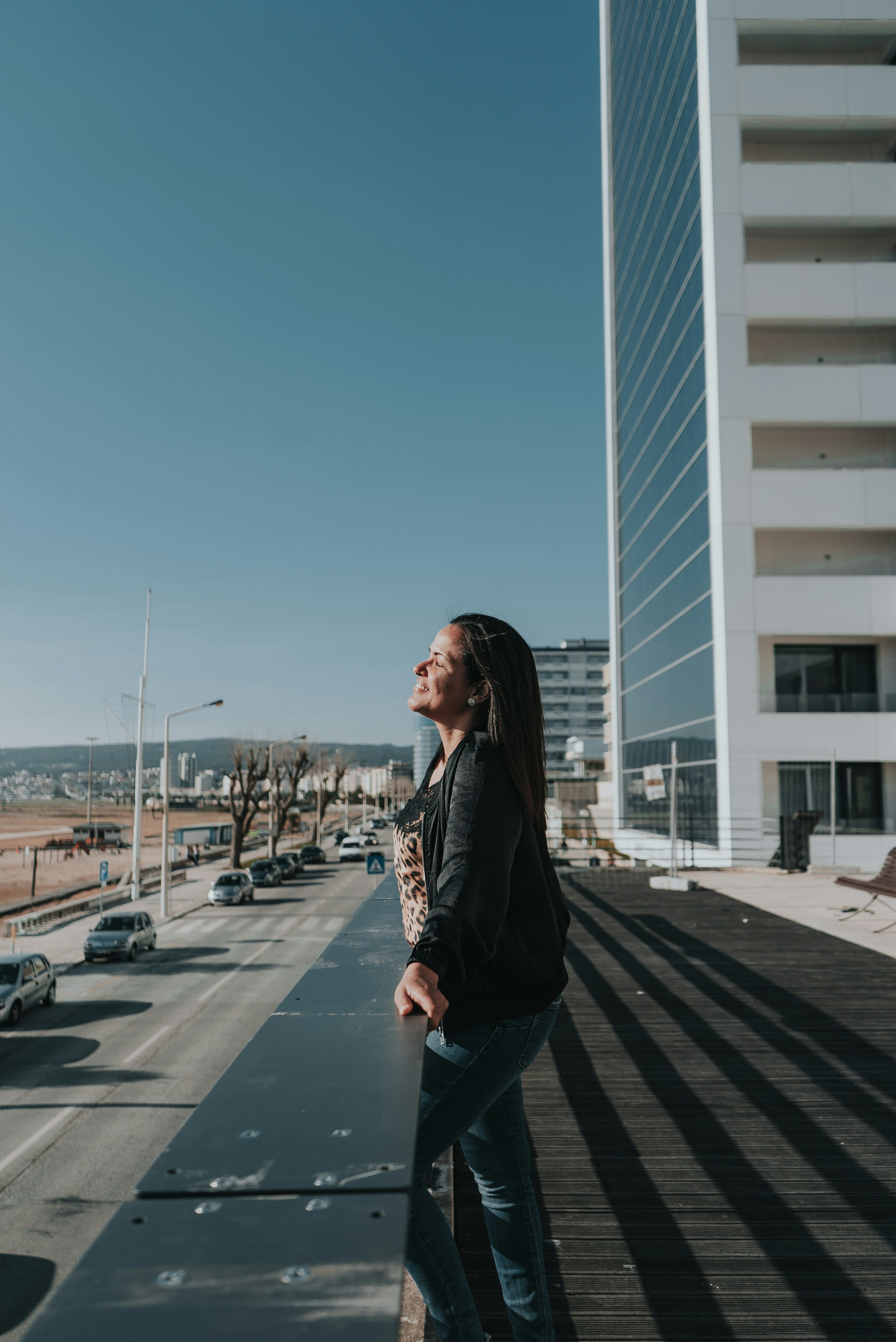 woman in black jacket standing on sidewalk during daytime