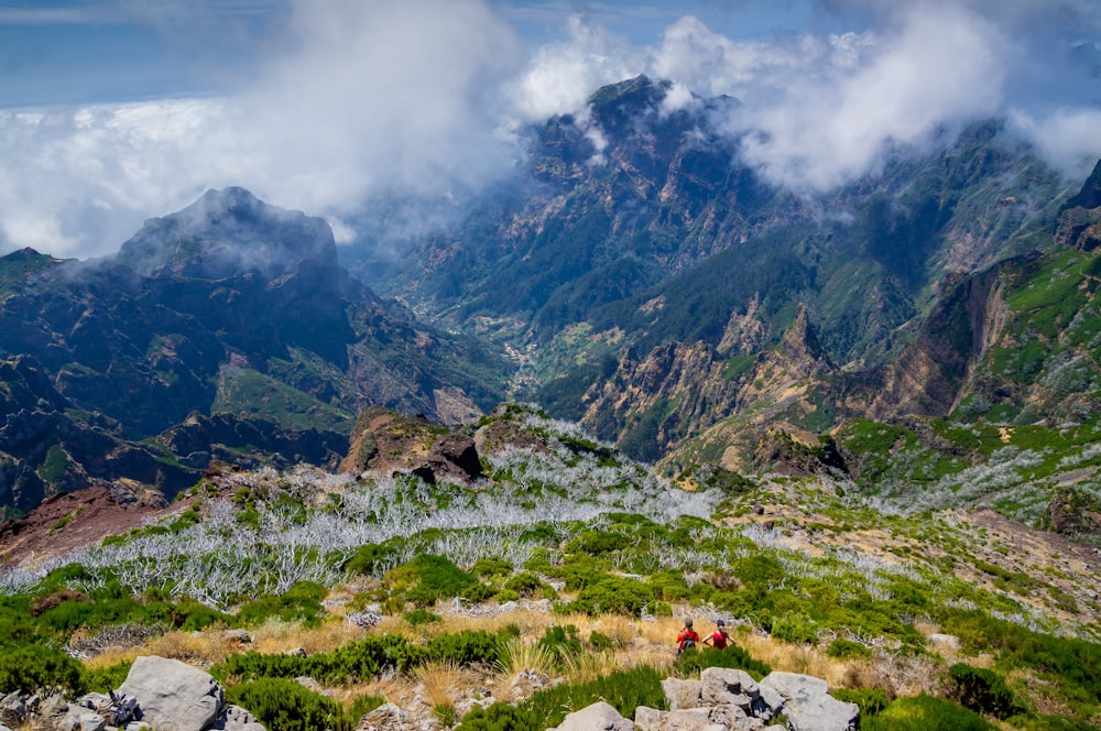 green grass field near mountain under white clouds during daytime