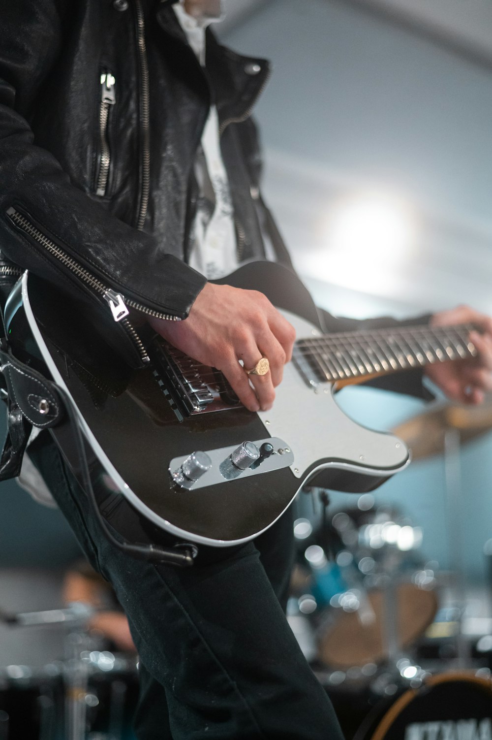 uomo in giacca di pelle nera che suona la chitarra elettrica