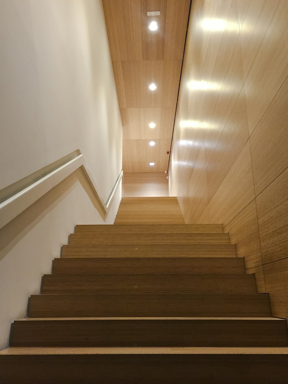 brown wooden staircase with white wall