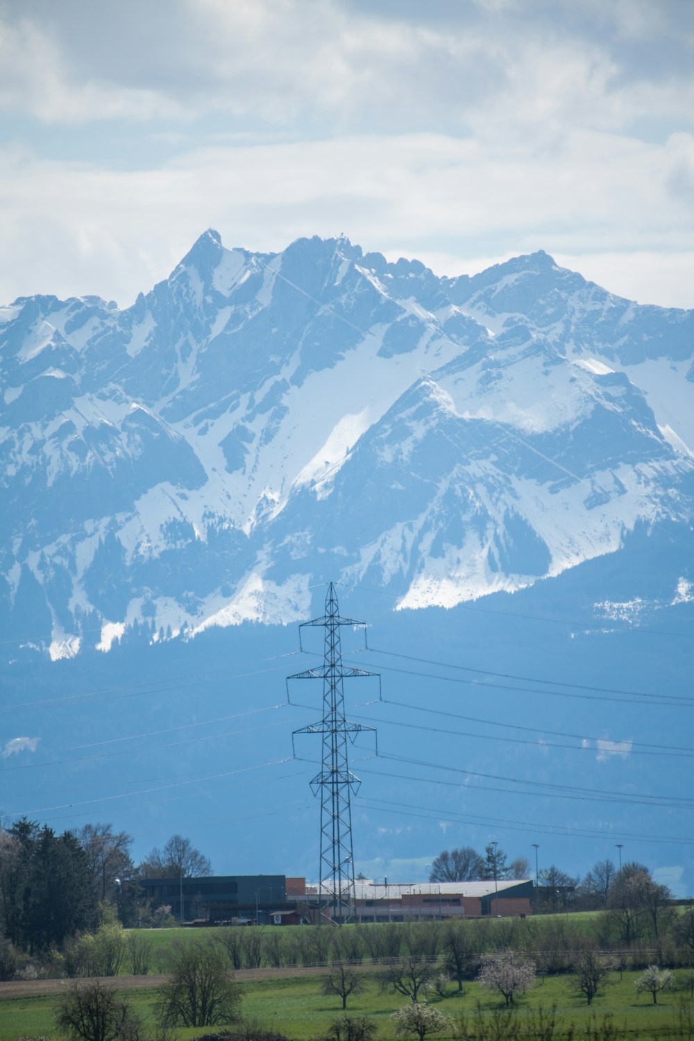 black electric post near snow covered mountain under blue sky during daytime