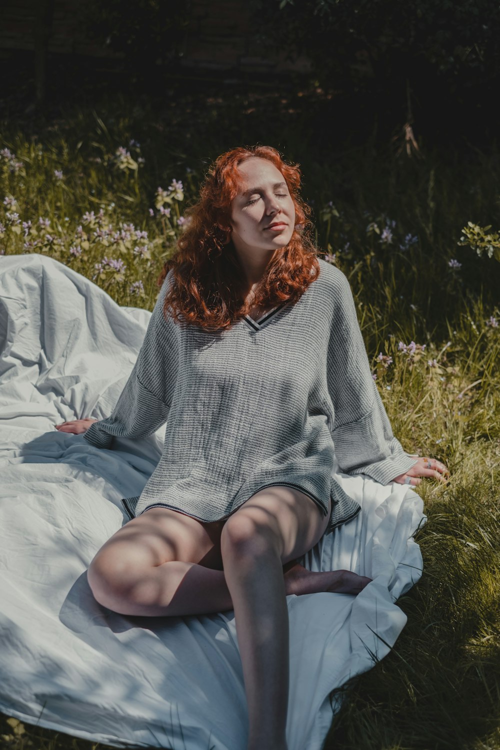 Mujer con suéter gris sentada sobre textil blanco