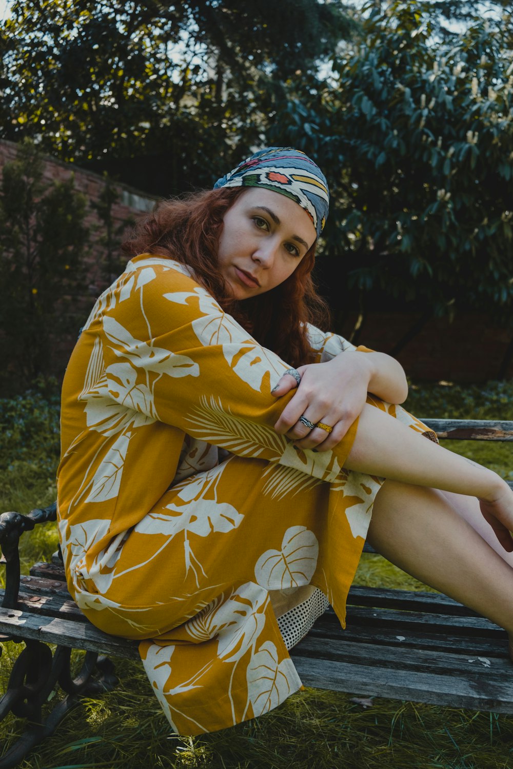 woman in yellow and white floral dress sitting on brown wooden bench