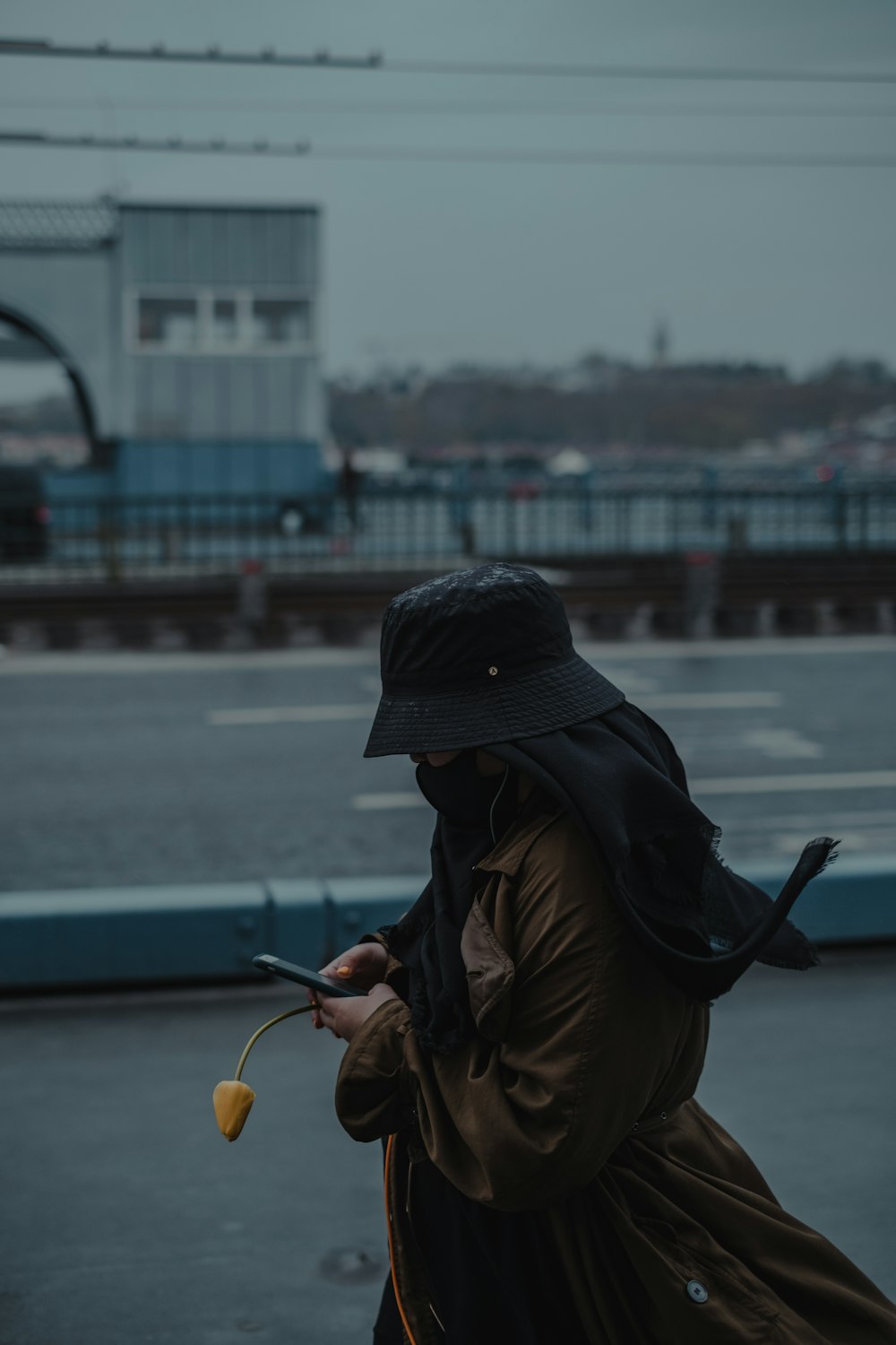 woman in brown jacket and black knit cap holding yellow bicycle during daytime