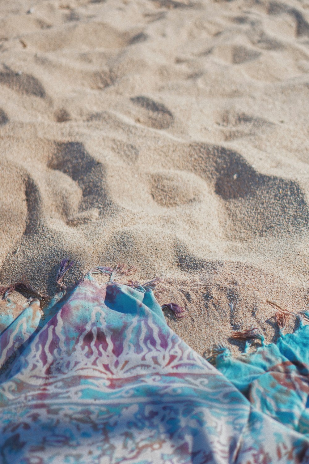 pink blue and white floral textile on brown sand