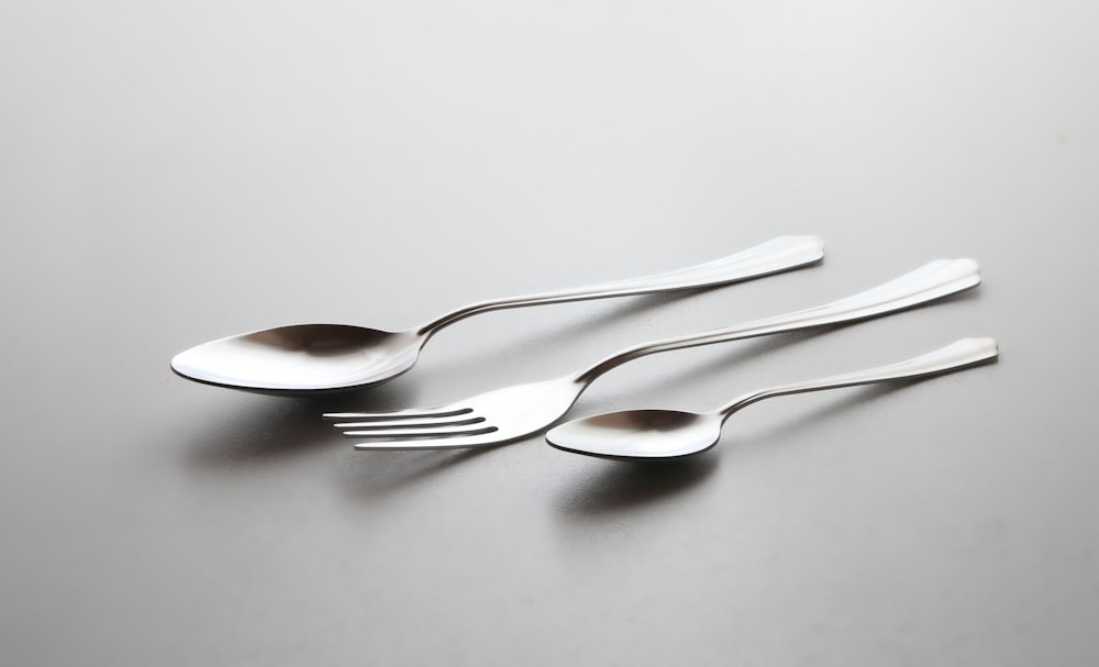 cucchiaio e forchetta d'argento su tavolo bianco