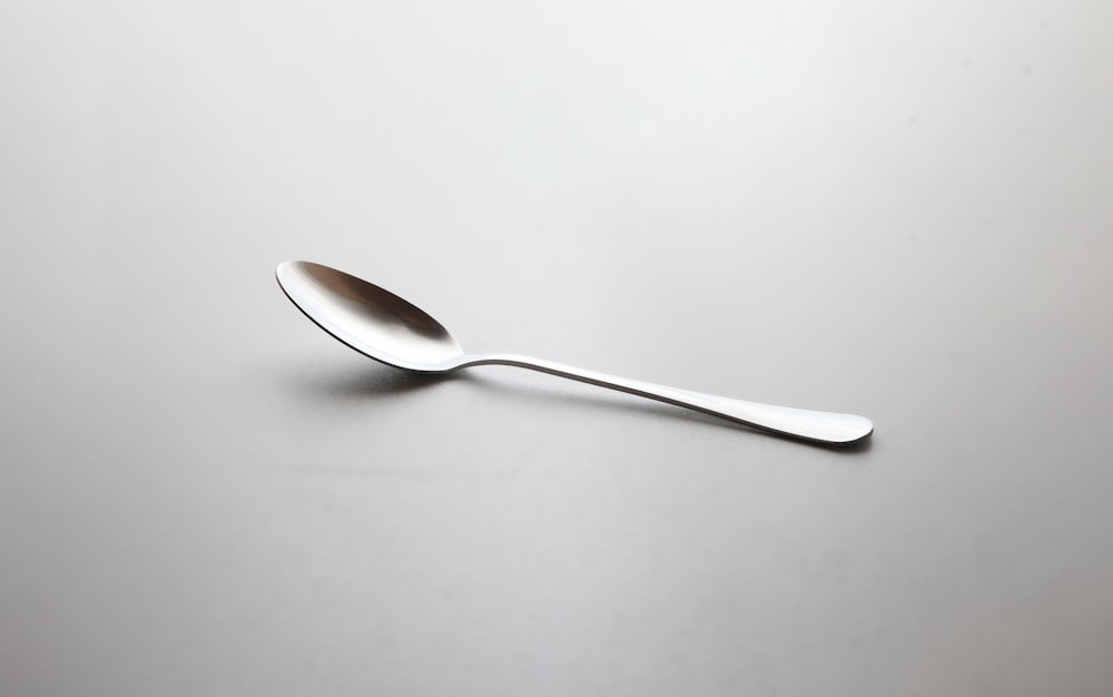cuchara de plata sobre mesa blanca