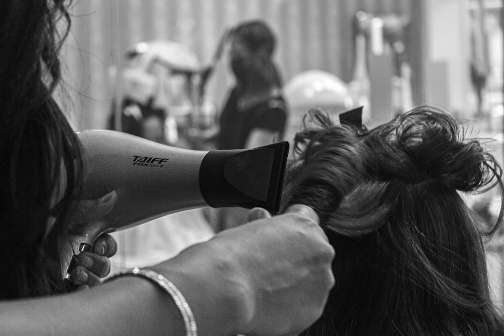 grayscale photo of woman holding hair blower