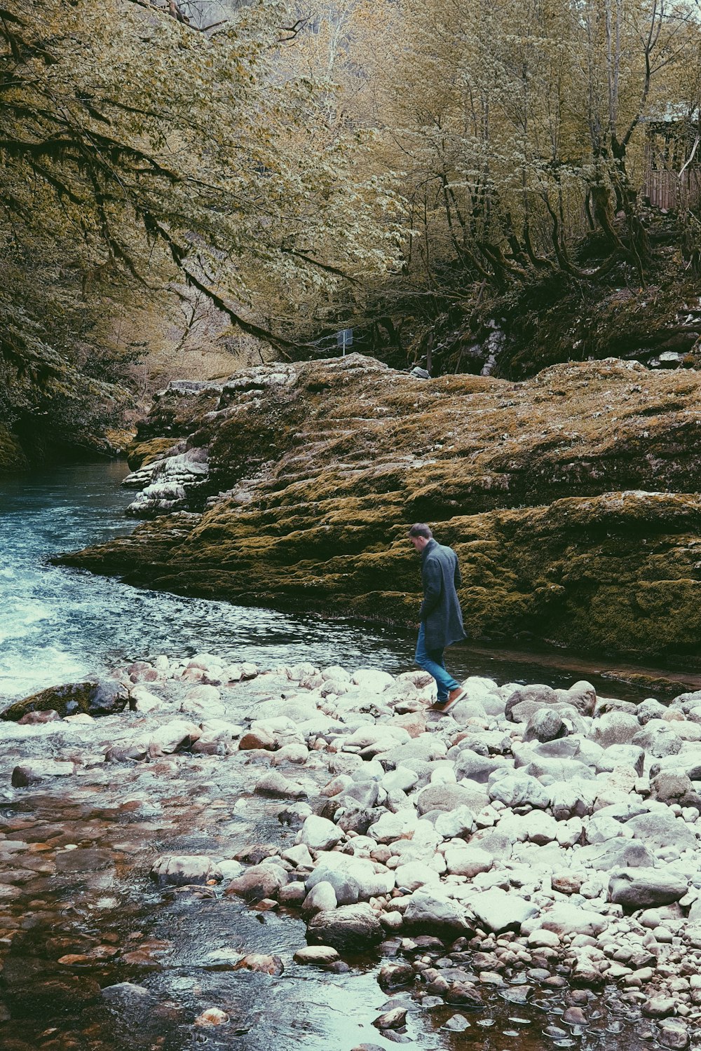 a man standing on rocks near a river