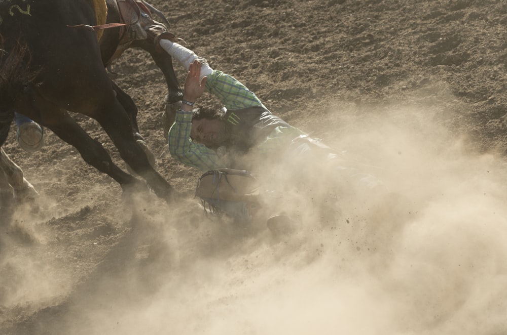 man in green jacket riding brown horse during daytime