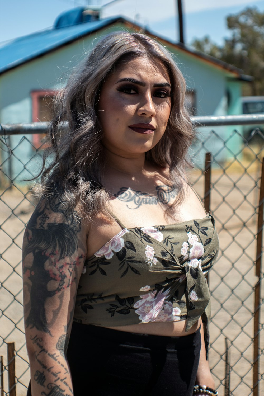 woman in black and white floral dress standing beside chain link fence