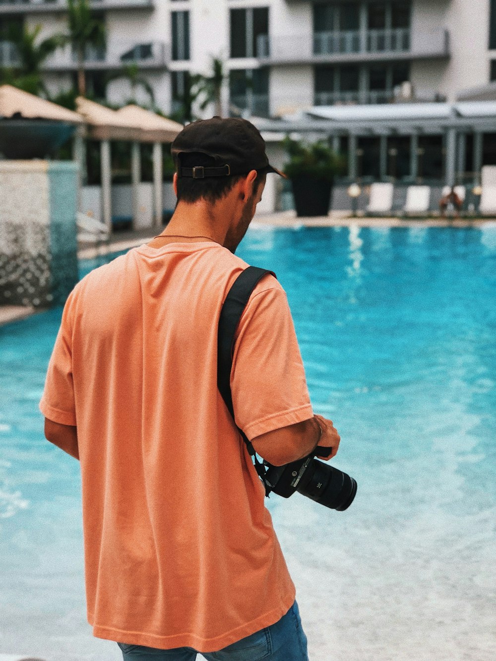 Foto Hombre con camisa naranja de manga larga y gorra negra parado cerca  del cuerpo de agua durante el día – Imagen Piscina gratis en Unsplash