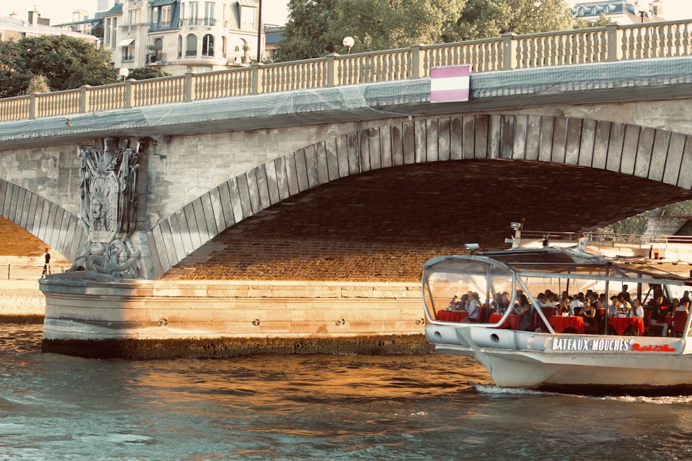 barca bianca e marrone sull'acqua sotto il ponte durante il giorno