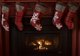 A blue stocking tag featuring a white layered snowflake design, dangling from a stocking above a glowing hearth.
