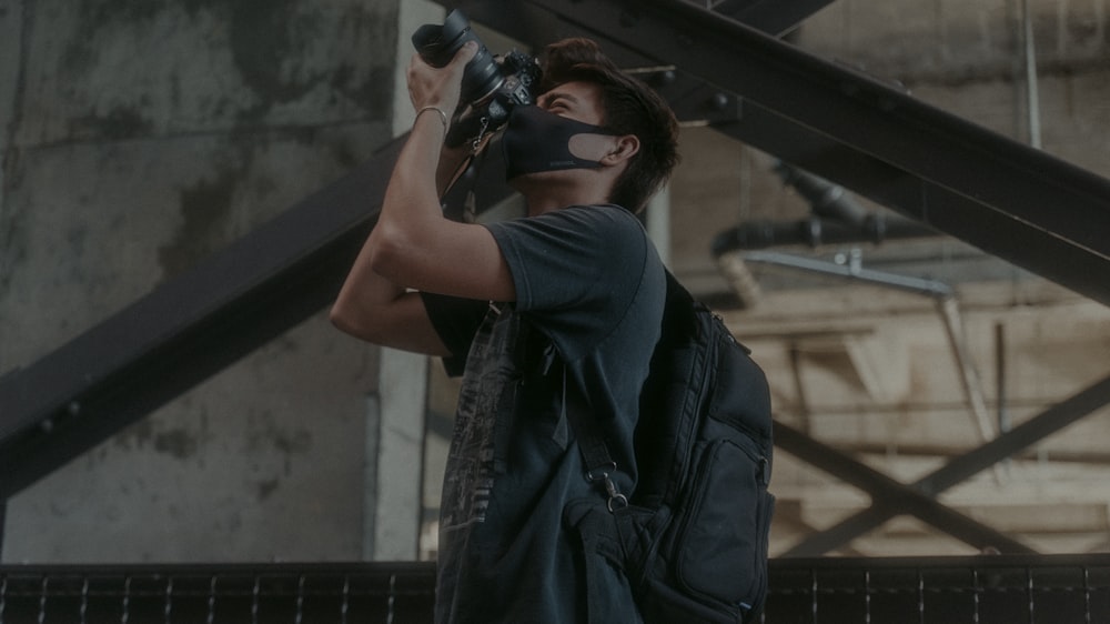 Mann in schwarzer Lederjacke mit schwarzer DSLR-Kamera