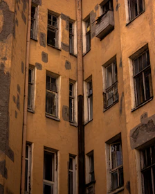 A close-up of a worn house facade with peeling paint and broken windows.