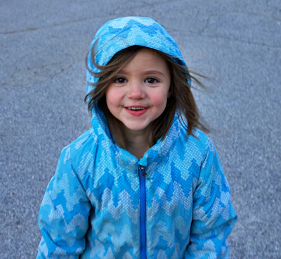 A smiling child holding a warm jacket donated by a local family.