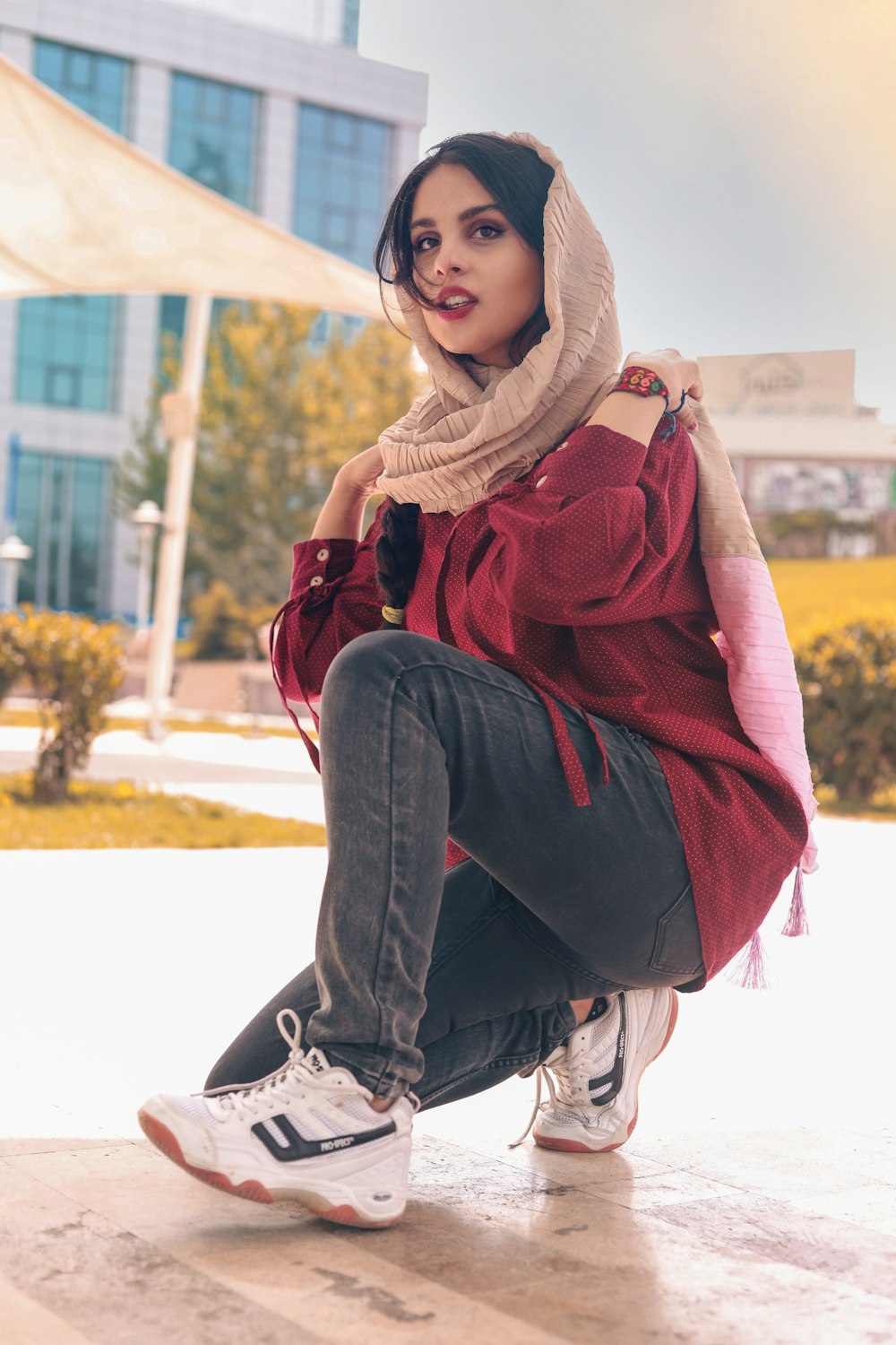 woman in brown hijab and blue denim jeans sitting on white concrete floor during daytime
