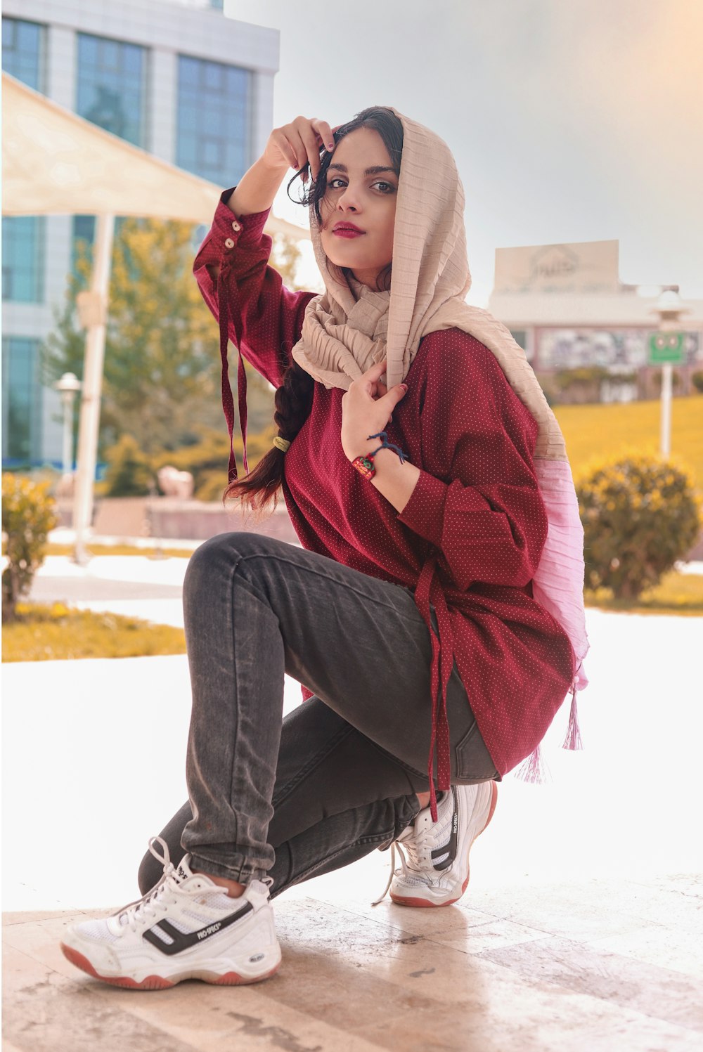 woman in red hijab and blue denim jeans sitting on white concrete bench during daytime