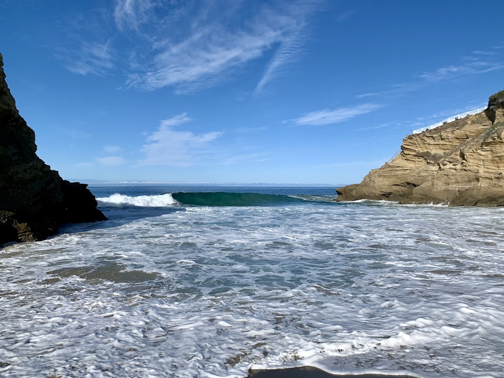 brown rock formation on sea under blue sky during daytime