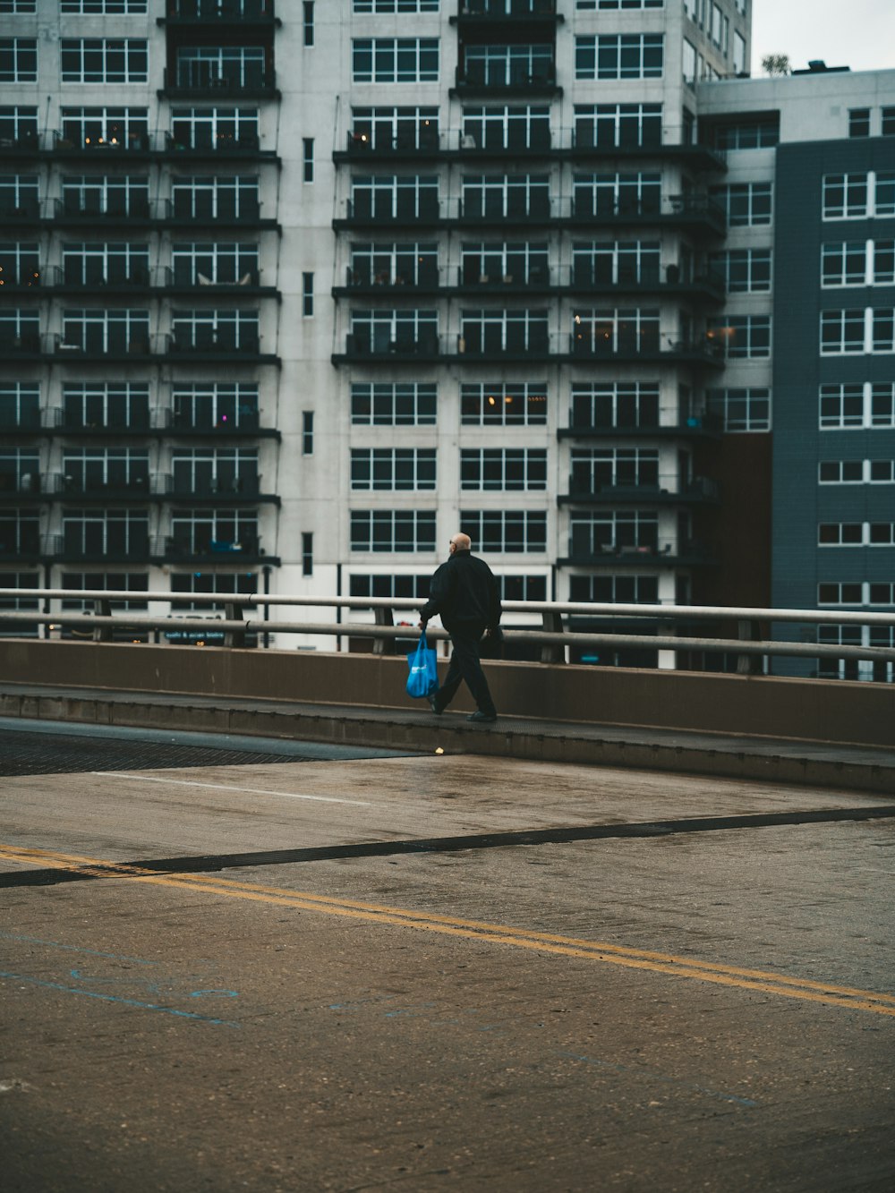 man in black jacket and blue denim jeans walking on road during daytime