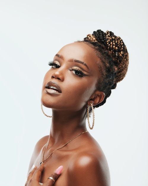 A confident Black woman wearing elegant accessories, smiling warmly in a stylish urban setting.