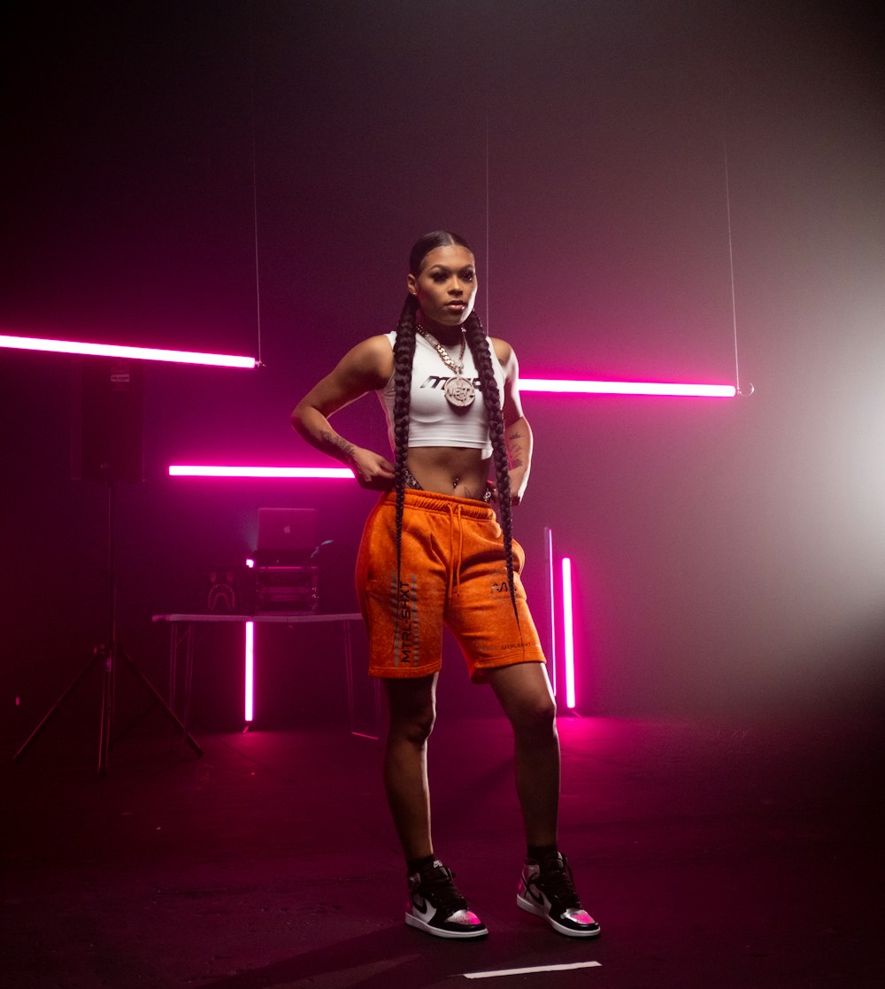 woman in white tank top and orange shorts standing on stage