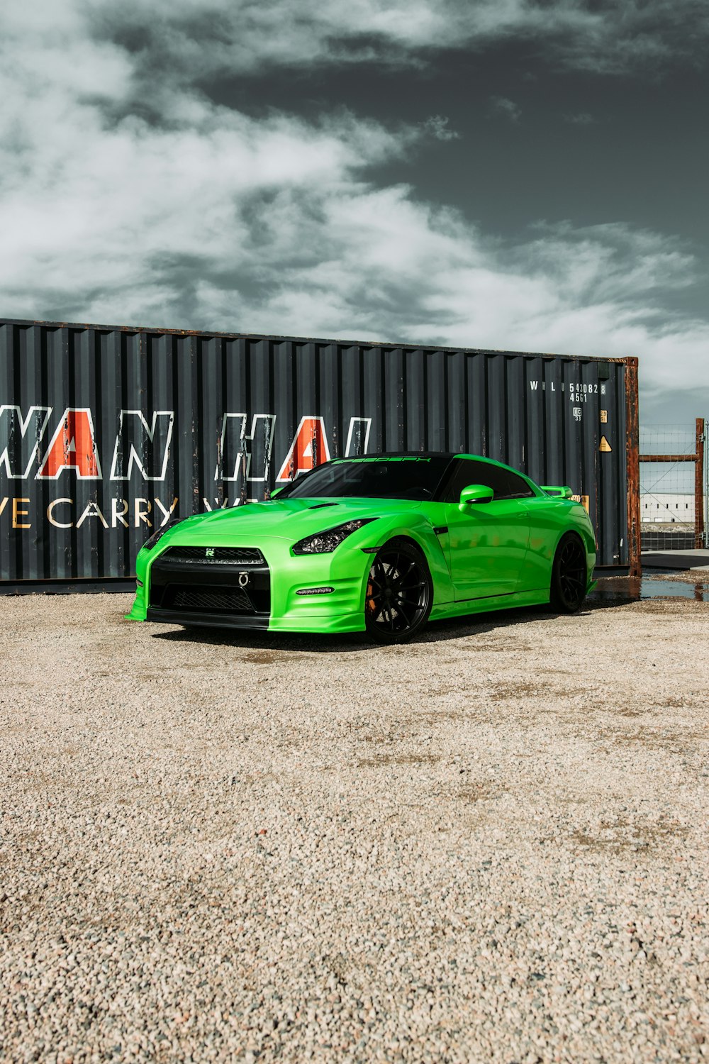 green ferrari sports car parked near black metal container