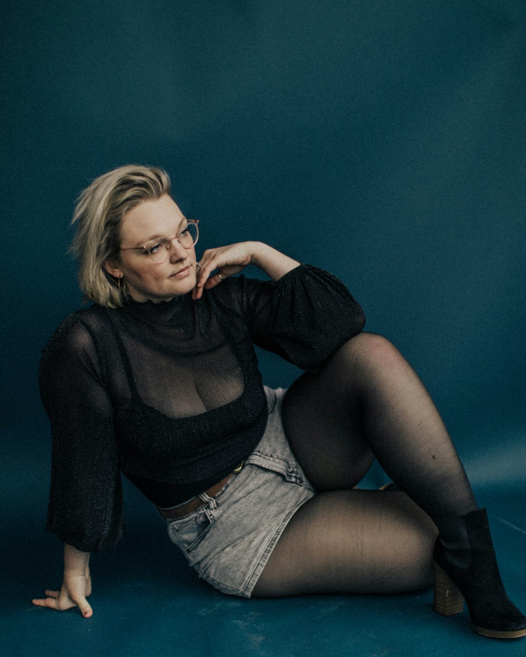 woman in black long sleeve shirt and blue denim shorts sitting on floor