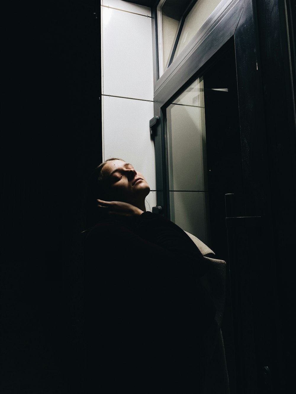 man in black coat standing near window