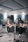 man playing electric guitar beside woman playing guitar