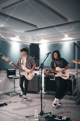 man playing electric guitar beside woman playing guitar
