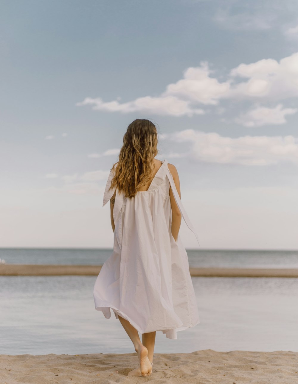 woman in white dress standing on beach during daytime